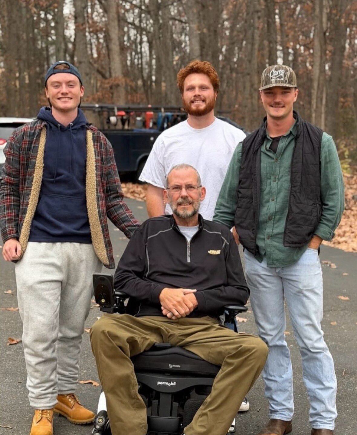Three brothers standing with a family friend in his wheelchair