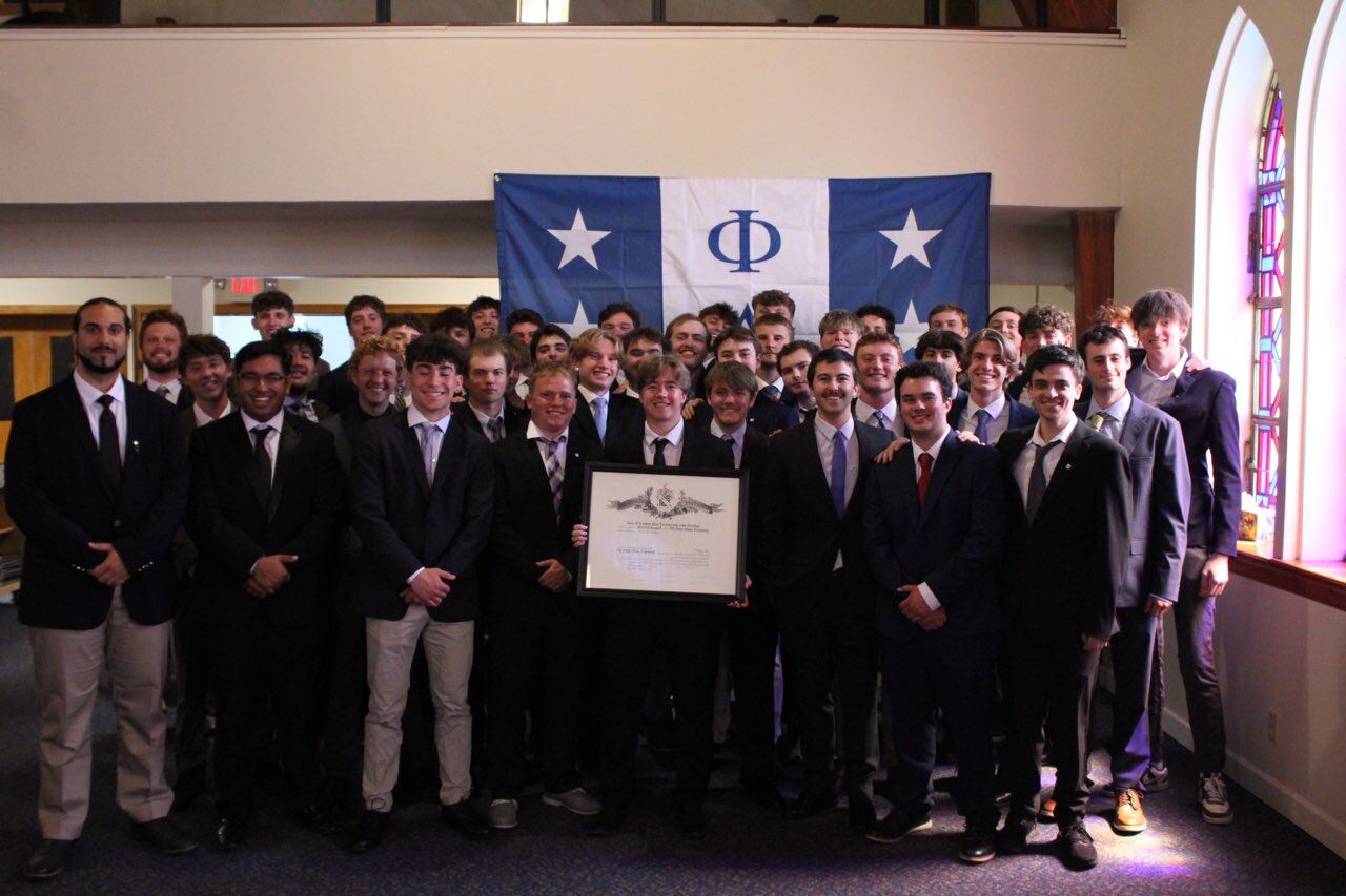 Virginia Mu brothers in suits holding the chapter charter beneath a Phi Delta Theta flag
