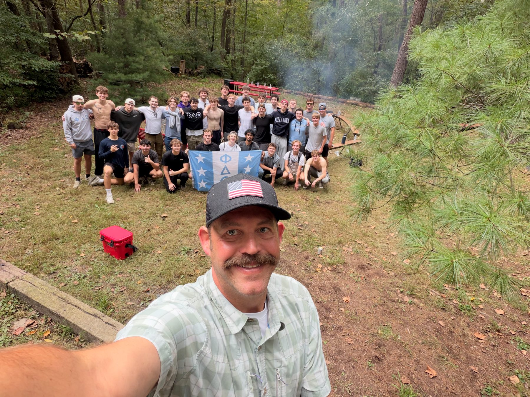 A large group of brothers outdoors behind a selfie