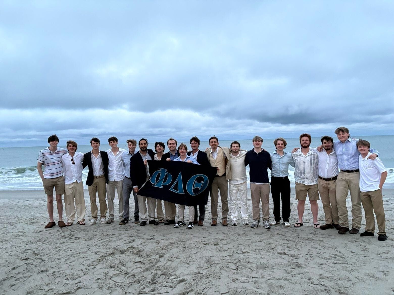 Brothers on the beach holding the Phi Delta Theta flag